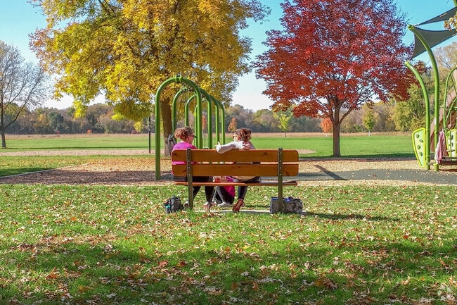 Friends relaxing on one of Central Park benches while watching their kids.
