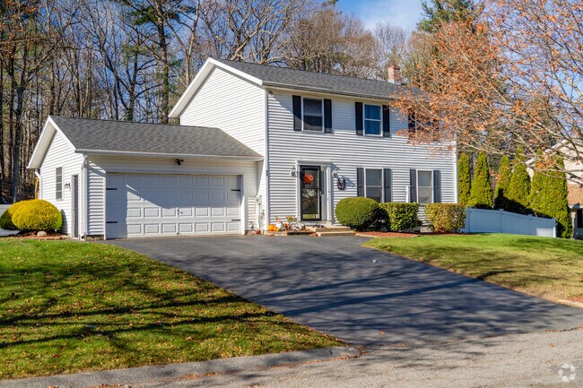 A colonial style home has an attached garage and a green lawn in West Fitchburg.