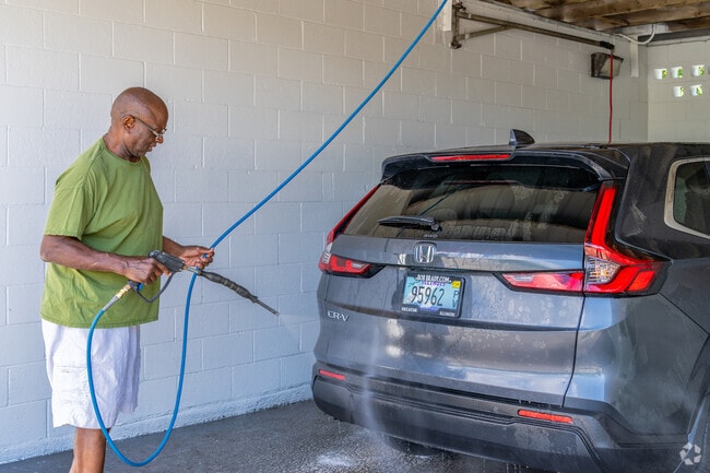 A Neighborhood Empowerment resident happily cleans his vehicle.