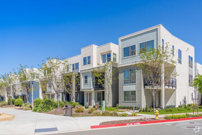 A row of modern condominiums sit nestled into a park-like setting.