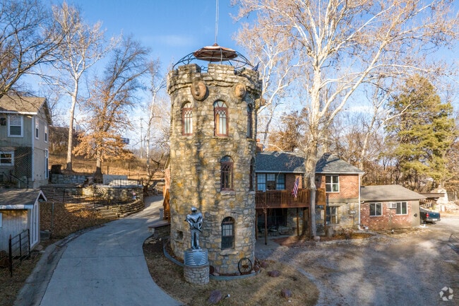 A stone tower rises beside this Briarcliff home, giving the property a storybook vibe—complete with medieval charm, rustic masonry, and even a metallic guardian keeping watch.