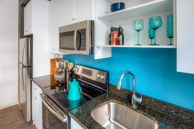 Kitchen with white cabinetry, granite countertops, stainless steel appliances and hard surface flooring