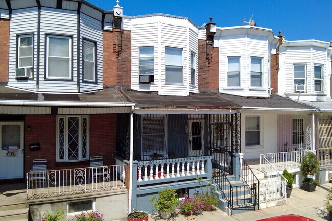 Two story brick and siding row home with covered porch in the Fairhill neighborhood.