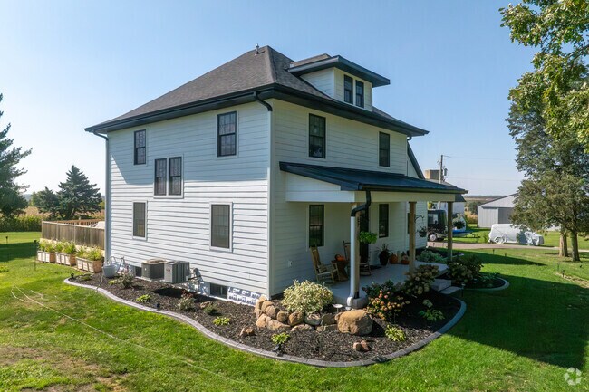 A farmhouse style home in Paris, Wisconsin is surrounded by gardens and wide, sunny lawns.