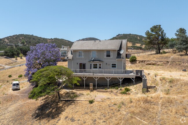 This Pine Canyon farmhouse-style home features a wraparound deck and hillside views.