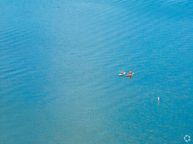 Two kayakers paddle across Lake Geneva’s rippling blue water on a sunny summer day.