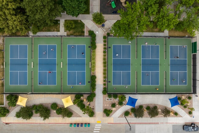 Blue and green tennis courts surrounded by trees at Butler Middle School.