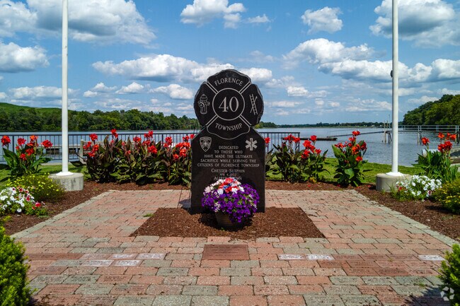 Memorial surrounded by flowers on the water at Volunteers Park in Florence, NJ.