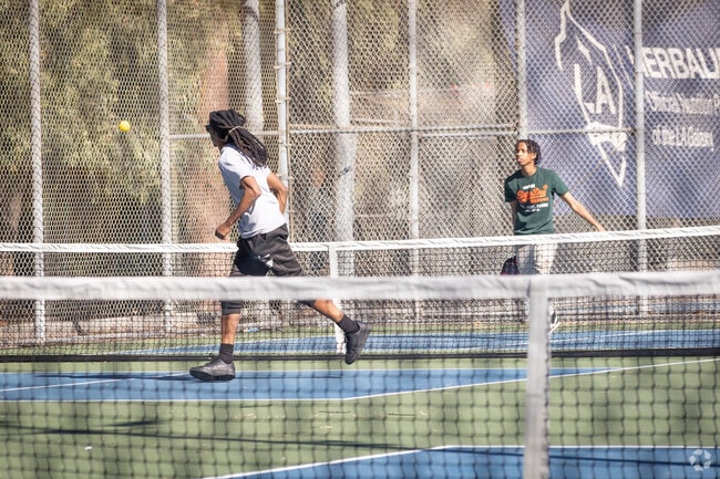 Residents in Nehyam play pickleball on well-maintained courts at DeForest Park.