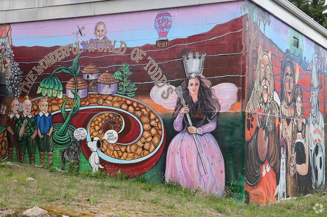 The entrance to Gloucester Crossing neighborhood is marked by a vibrant mural that creatively blends imagery from The Wizard of Oz with local Beverly landmarks and references, offering a whimsical welcoming feel.