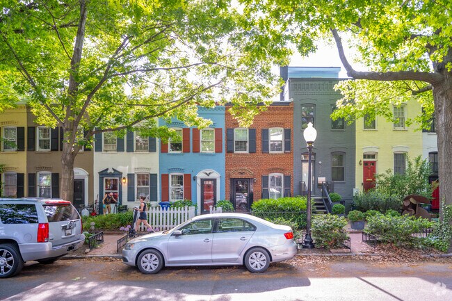 People walking down the shaded, residential streets of Foggy Bottom.
