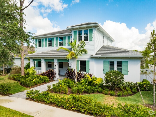 Modern two-story house with colorful shutters and a well-maintained yard in Abacoa.