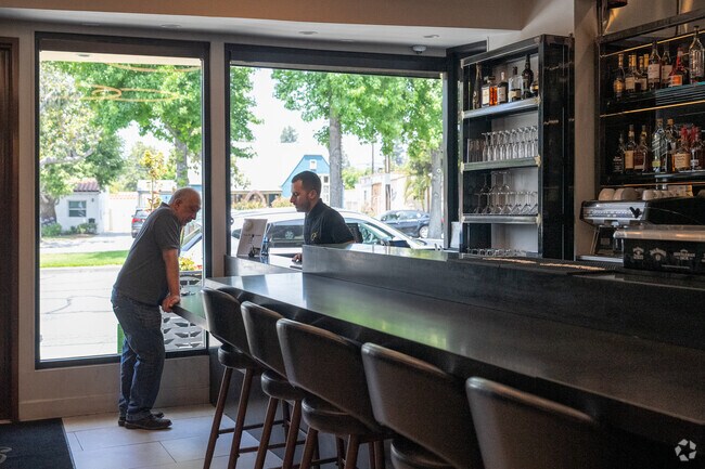 The sleek, modern interior—with glass walls, wood‑panel accents, and elegant Armenian artwork at Pardis restaurant —creates an upscale yet welcoming dining environment.