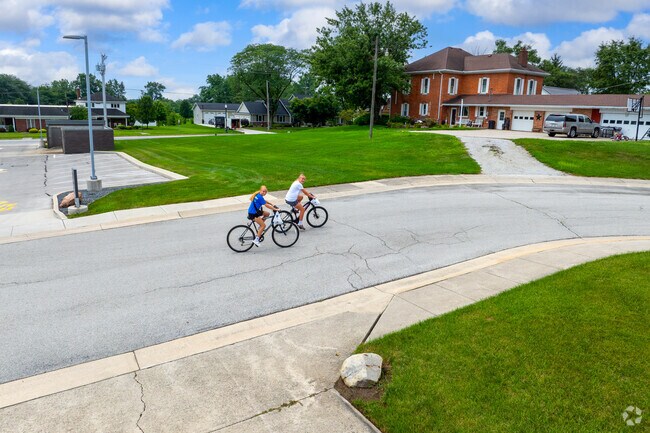 Bicyclists enjoy a quiet street in Coldwater, Ohio lined with lawns and two-story homes.