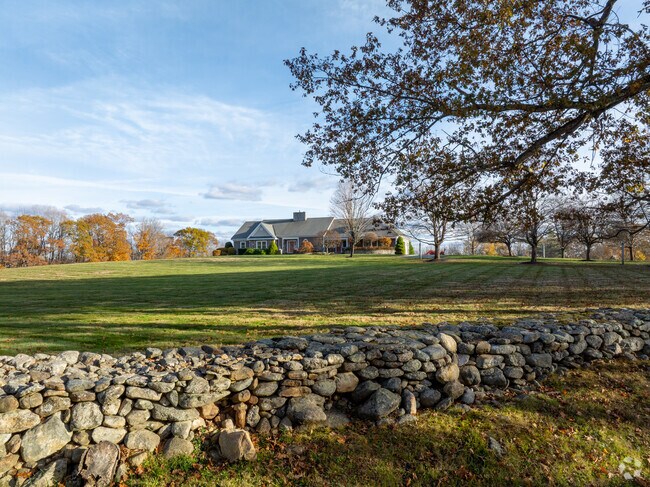 A beautiful ranch-style home in Rindge, sits atop a wide open field framed by a classic New England stone wall.