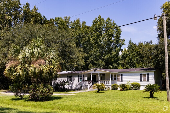 A manufactured home on a large lot with lush greenery in Seabrook.