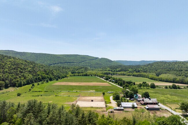 An aerial view of Brookline reveals wide-open fields, quiet country roads, and forested hills stretching  into the distance.