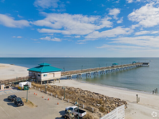 The Buckroe Beach Pier has a parking lot and a walkway.