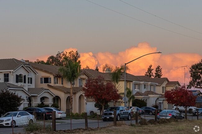 Large split-level homes of Village One sit in front of bright, pink cumulonimbus clouds.