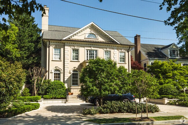A truly stately stone Italianate house with decorative bushes in Cathedral Heights.