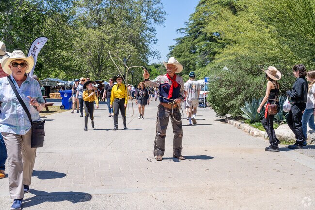 A cowboy shows off his tricks while visitors walk by at the Cowboy Festival in Newhall.