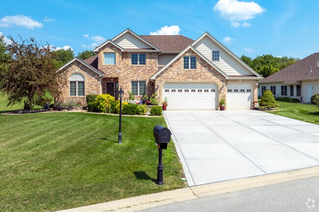 Elegant two-story suburban home in Winfield, Indiana with a spacious driveway, three-car garage, and pristine landscaping.