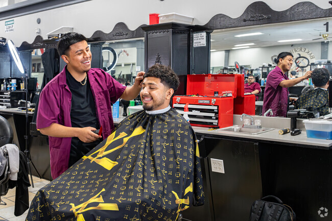 A student at Bakersfield Barber College in Hillcrest prepares to cut hair on his friend.