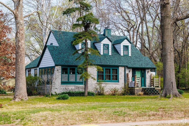 An older 2 story home in the Sequiota neighborhood is flanked by large trees.