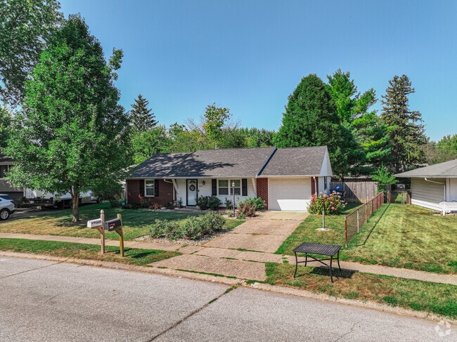 A Vinton Woods ranch, shows off a brick and vinyl facade, shaded by a tall tree.