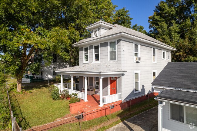 A four-square style house with a large front porch and a small front yard.