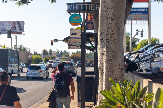 A small group of people waiting in Friendly Hills for the Whittier bus line to arrive.