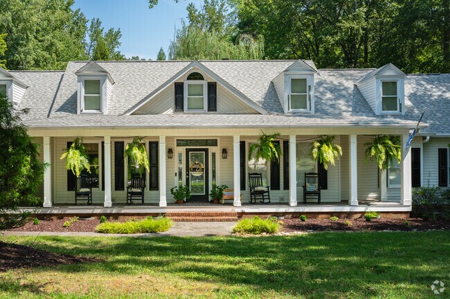 A cape cod style home with a large front porch and hanging plants in North Simpsonville.