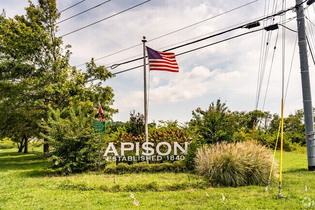 The Apison neighborhood sign with lush landscape and American flag.