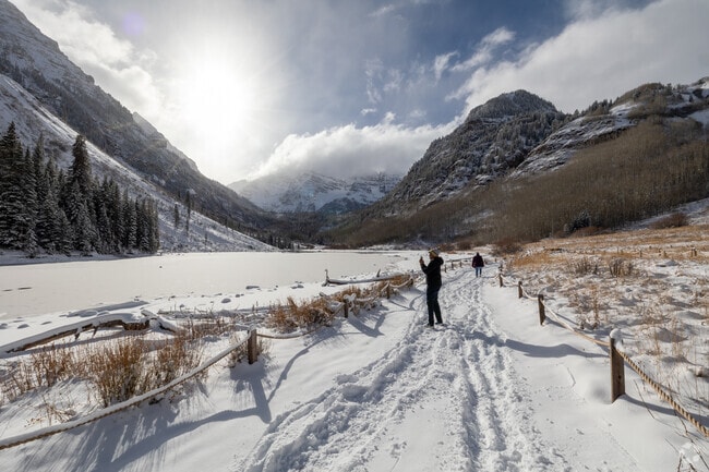 Hikers take in the breathtaking views of frozen Maroon Lake and towering peaks.