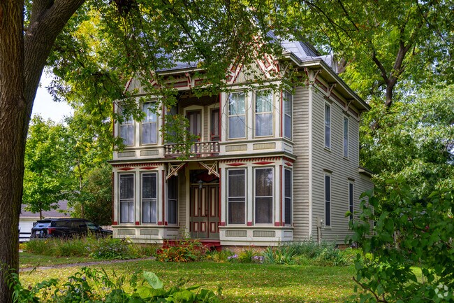 Victorian homes are shaded by leafy green trees.