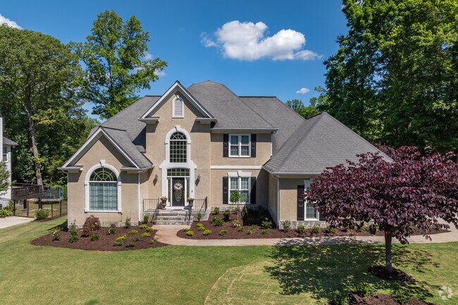 Nestled in the charming Medlock Bridge community, this stunning traditional-style home boasts a refined and sophisticated neutral exterior palette, harmoniously complemented by beautifully arched windows that exude architectural elegance.