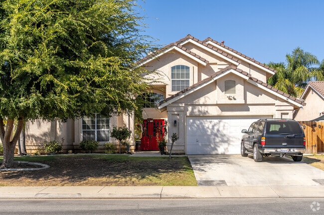 An expansive multi-story home with a vibrant red door stands out in charming Westlakes.