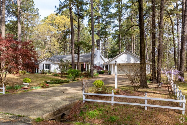 A ranch style home is surrounded by large pines on a large lot in Magnolia.