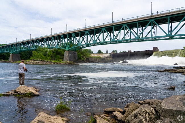 A fisherman casts from the rocky shore by the Gill–Montague Bridge and dam in Turners Falls.
