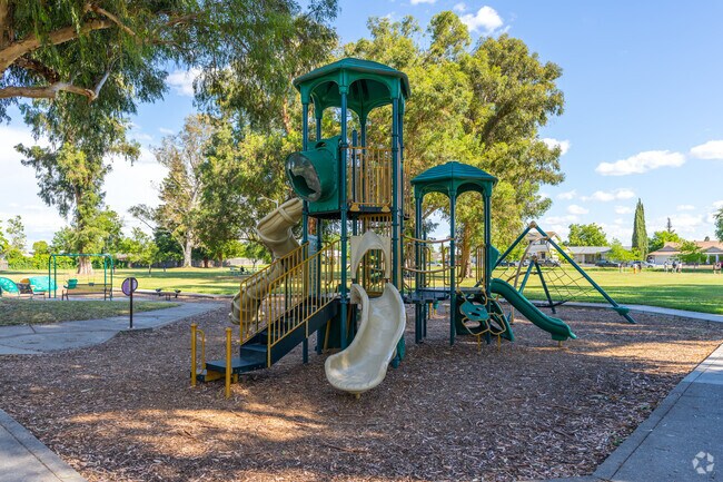 The playground at Pollack Ranch Park is shaded by tall trees.