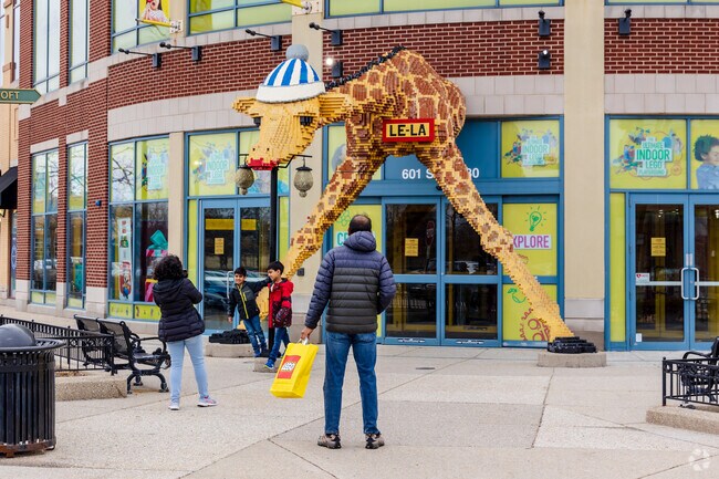 Kids posing for a photo taken by their mother in front of Lego store at Streets of Woodfield.