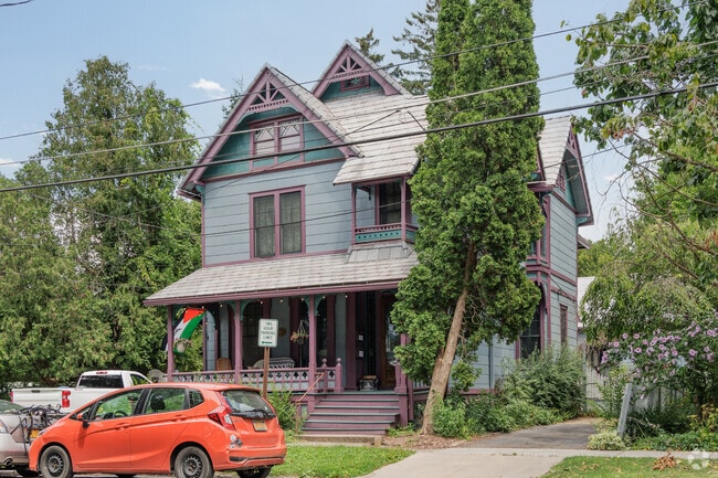 A Victorian style house sits on a shady street in Downtown Ithaca.