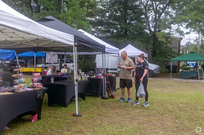 Shoppers browse a variety of handmade goods and crafts displayed under vendor tents at the Ridgeville Farmers Market, enjoying a relaxed weekend outing.