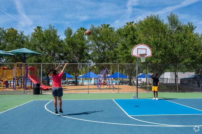 Parents shoot some hoops while the kids play on the Simpson Park 