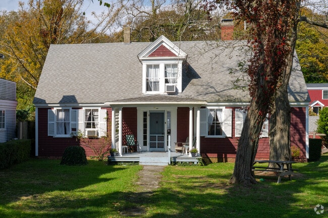 Red-sided cottage with white trim sits among trees in Provincetown.