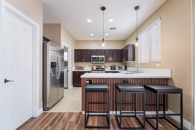 Kitchen with stainless steel appliances, a kitchen bar, hanging light fixtures, light wood-style flo