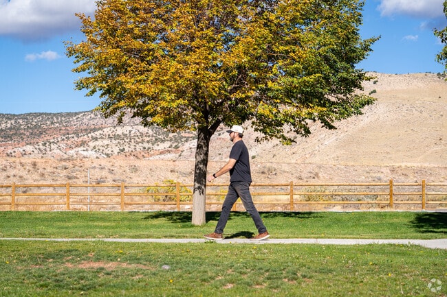 Residents strolls through Centennial Park framed by autumn trees and distant mountains.