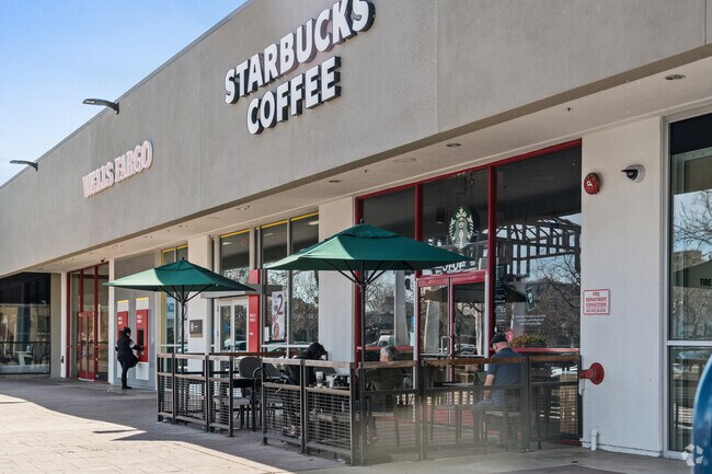 Starbucks patrons enjoy their favorite brew under shaded tables near Forestland.