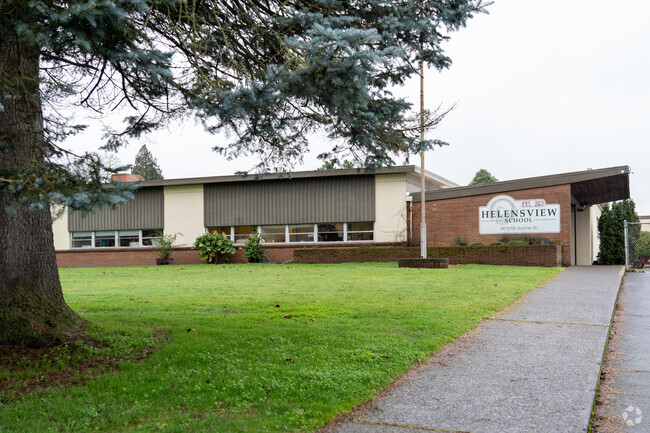 A large grassy area sits in front of the school entrance.