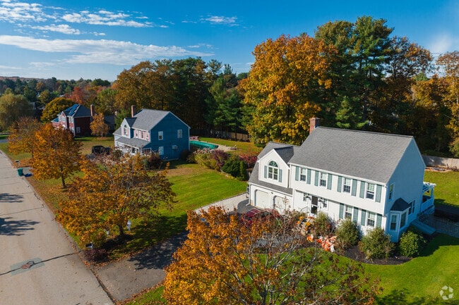 Colonial Revival and Cape Cods are lined up along one another on a quiet residential street.